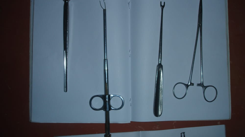 Tonsillectomy hand-instrument set on a white background: a wire-loop tonsil snare with finger rings, tonsil forceps, an artery forceps, and a probe