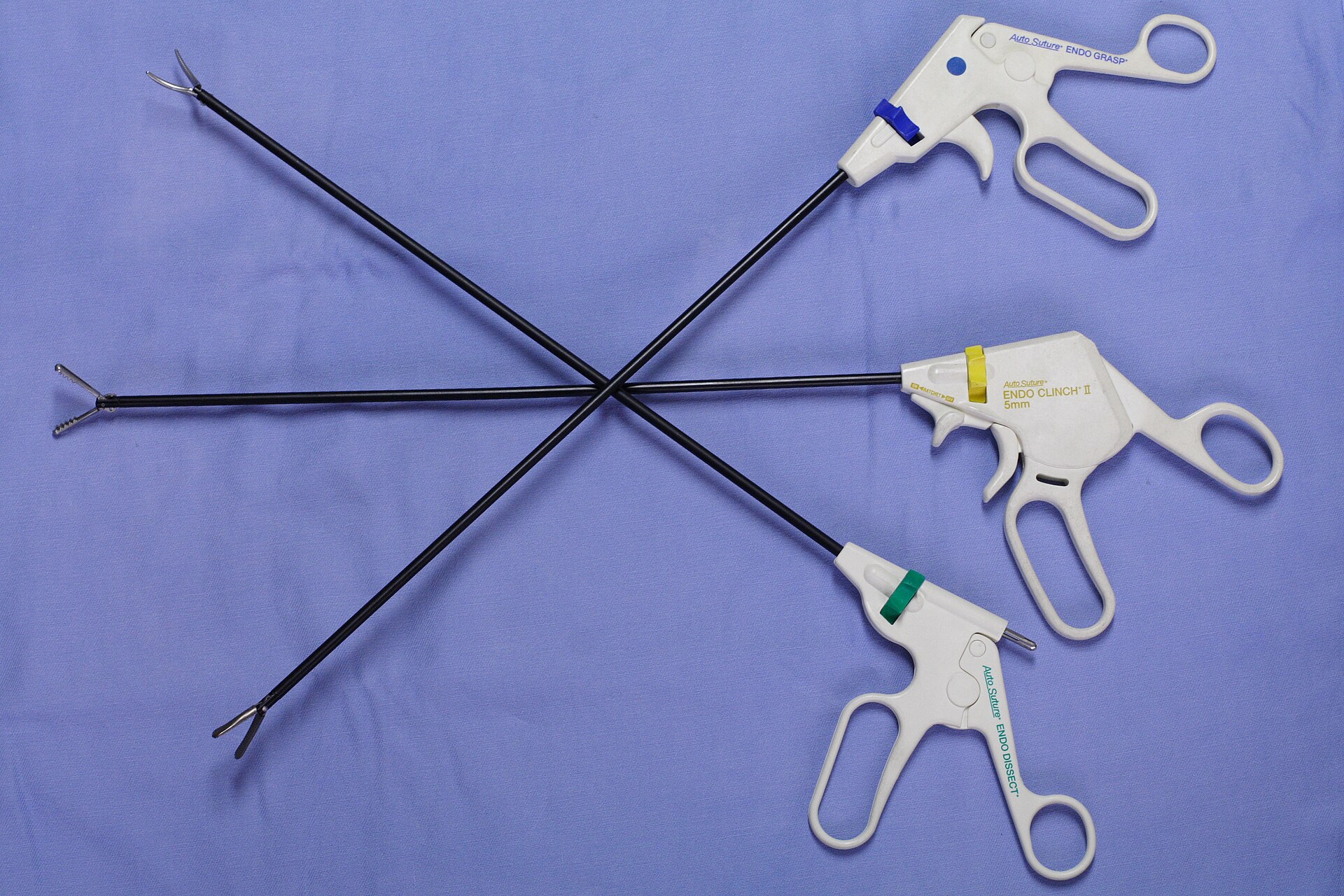 Laparoscopic hand instruments — endo grasp, clinch, and dissect pistol-grip handles with long shafts — on a surgical drape
