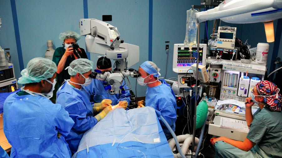 A Zeiss ophthalmic operating microscope positioned over a draped patient during cataract eye surgery