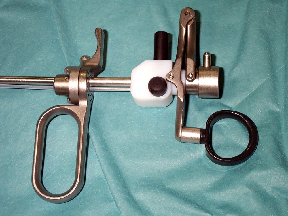 A resectoscope working element with finger-ring handles, a ratchet spring, and a telescope channel, laid out on a surgical drape
