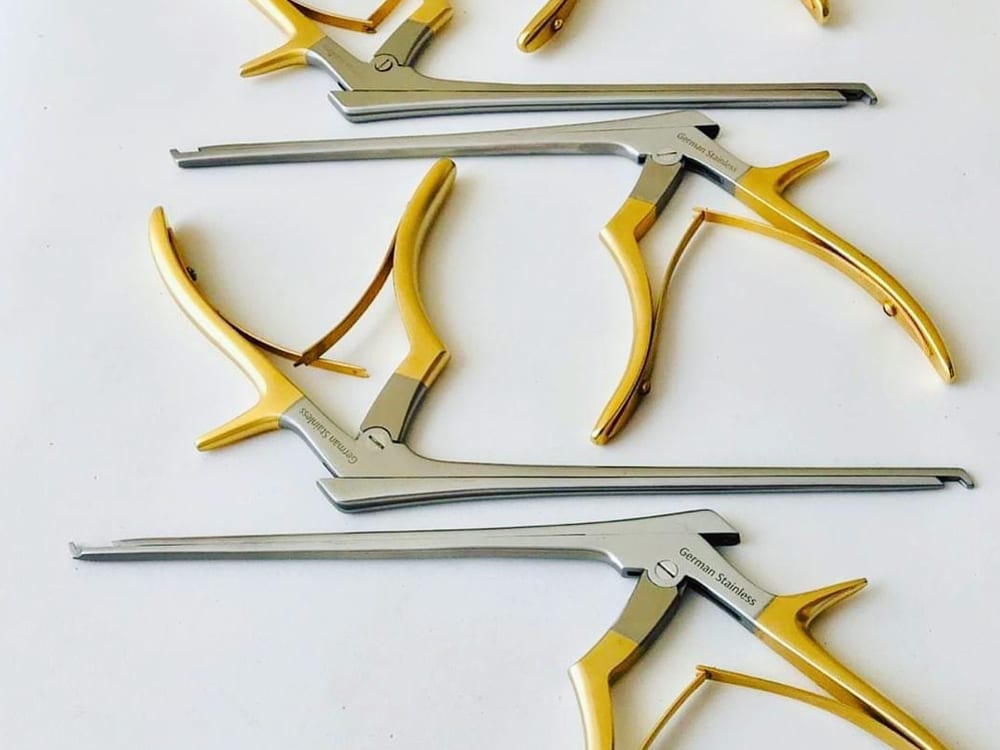 A set of Kerrison rongeurs — bone-biting neurosurgical punches with pistol-grip handles, slender shafts, and angled cutting footplates, used in spine and cranial procedures