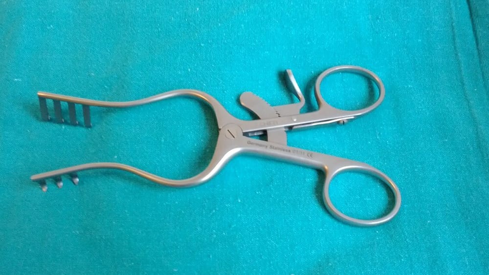 Weitlaner self-retaining surgical retractor with pronged blades, a ratchet locking bar, and finger-loop handles