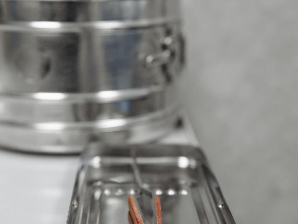 A stainless-steel rigid surgical sterilization container and a perforated instrument tray/basket, shown as they sit — the kind of packed container we buy