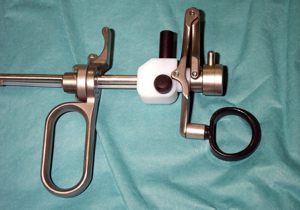 A used rigid endoscopic surgical instrument — a resectoscope working element with a finger-ring handle and telescope shaft — laid out as-is on a surgical drape, showing normal wear from prior clinical use