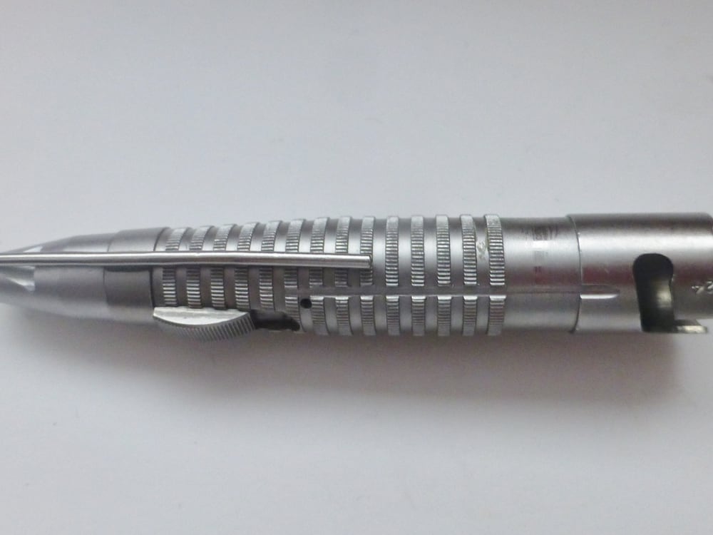 A used high-speed rotary surgical handpiece with a knurled grip and bayonet coupling, laid out as-is, showing normal wear from prior use