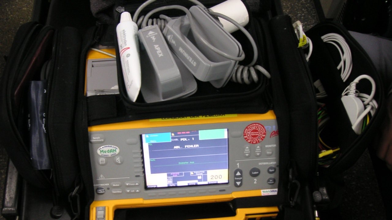 A portable defibrillator/monitor with its electrodes, paddles, and accessories.