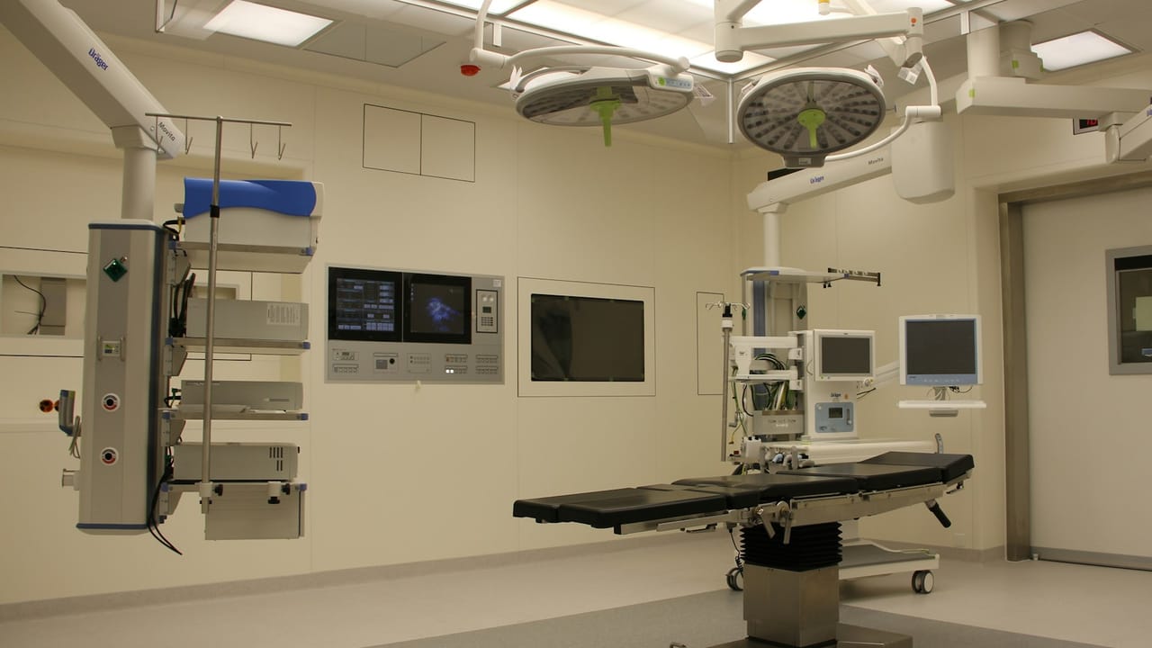 Operating room equipment — surgical lights, table, anesthesia workstation, and carts.