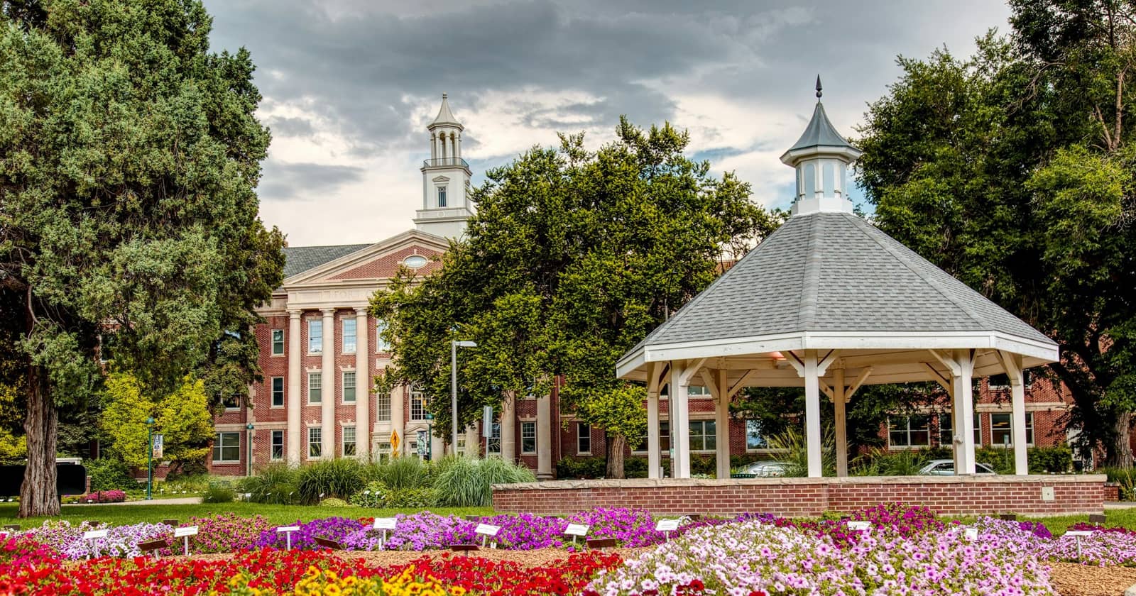 Flower gardens and a white gazebo before a brick hall, Fort Collins, Colorado