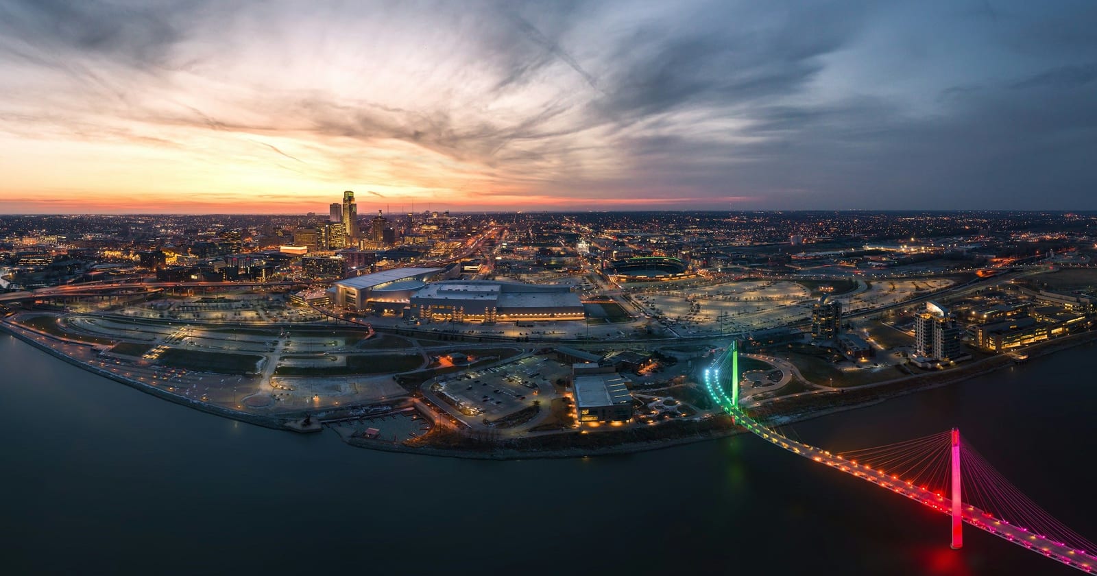 Aerial view of the Omaha riverfront and a lit pedestrian bridge at dusk, Nebraska