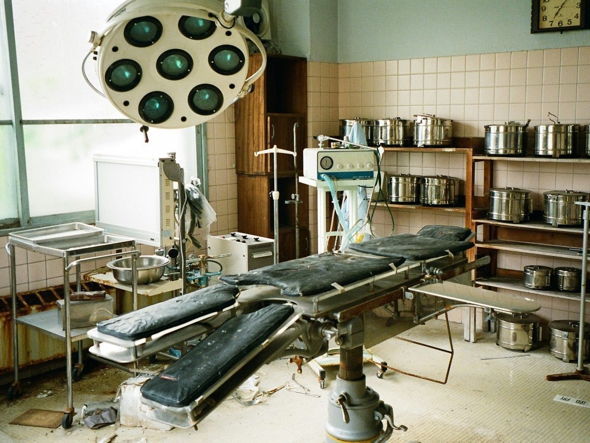 Operating room left with an old surgical table, light and equipment