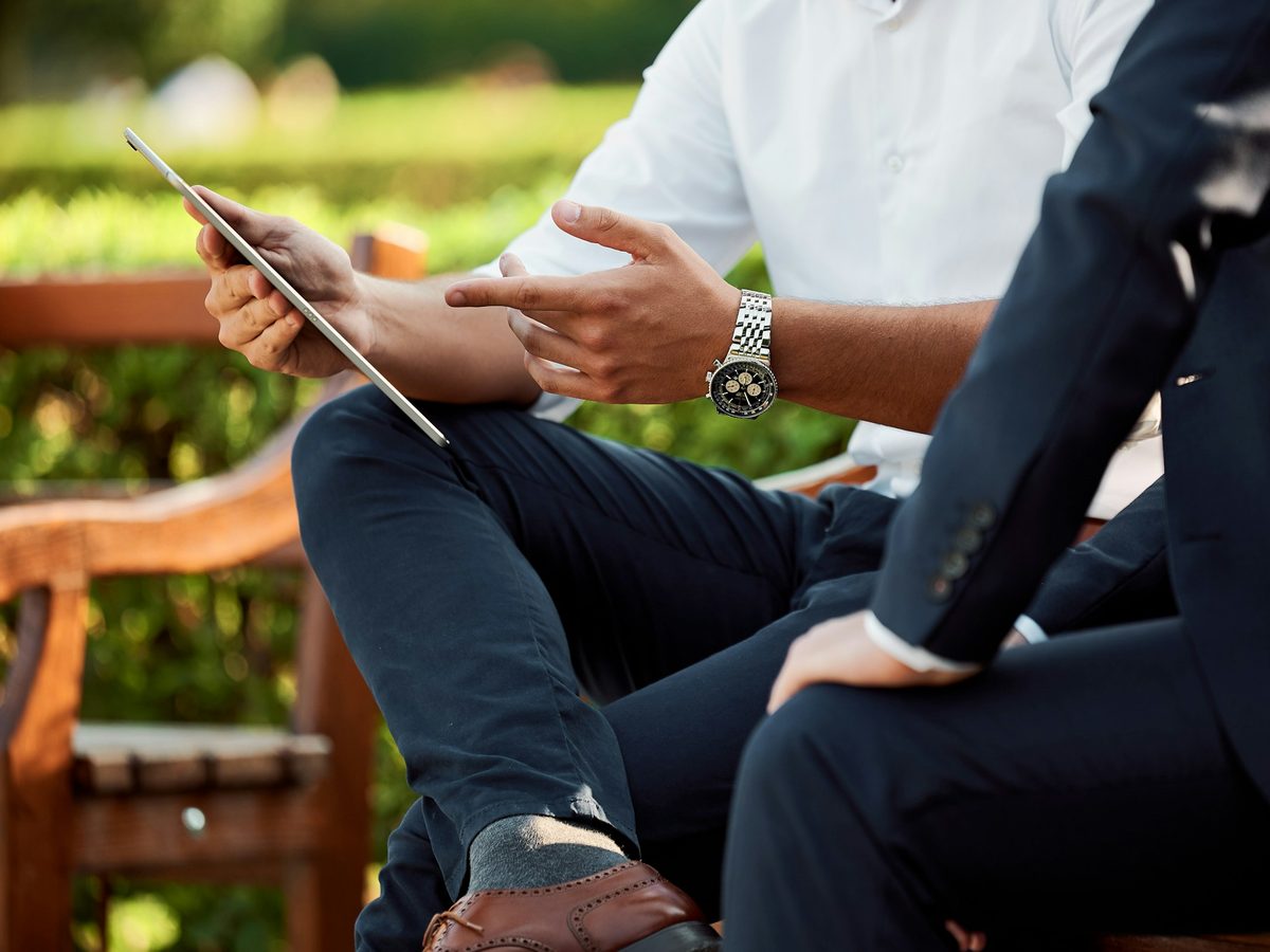 Two people in business clothes talking over a tablet